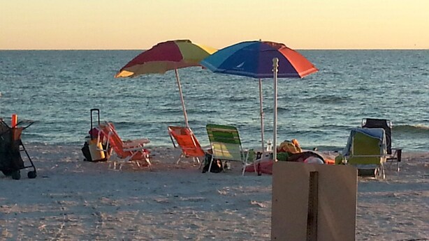 Una playa con varios sombrillas y sillas de playa de colores.
