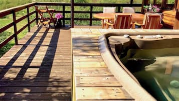 Una terraza de madera con un jacuzzi, mobiliario exterior y una vista panorámica.