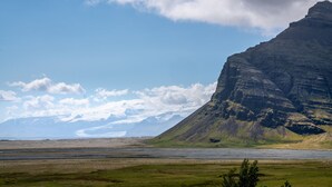 A mountainous landscape with a river in the foreground and a glacier in the distance. - Ekra Glacier Lagoon (Reynivellir)