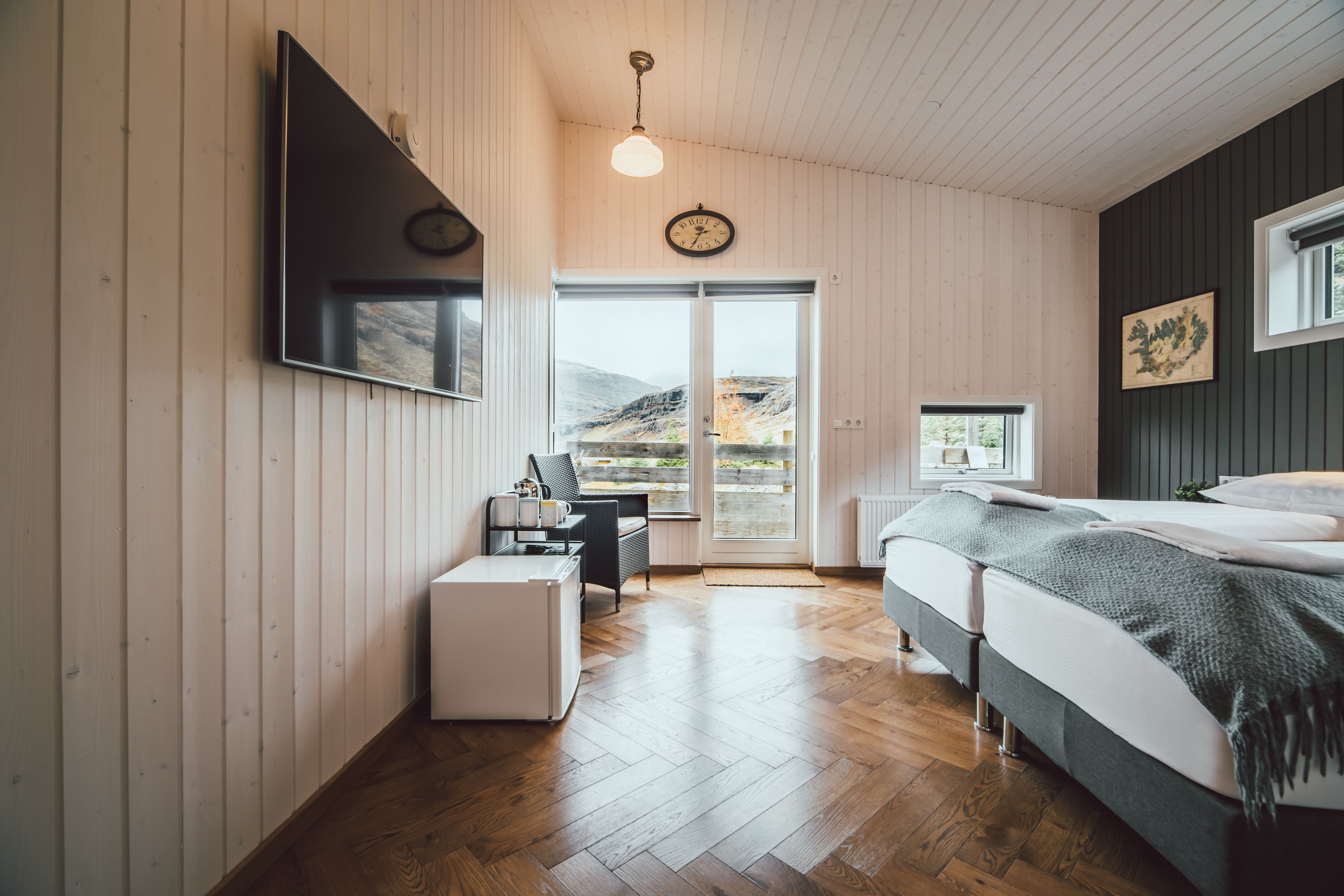 Ein Schlafzimmer mit Bett, Schreibtisch, Stuhl, Fernseher und einem Fenster mit Blick ins Freie.
