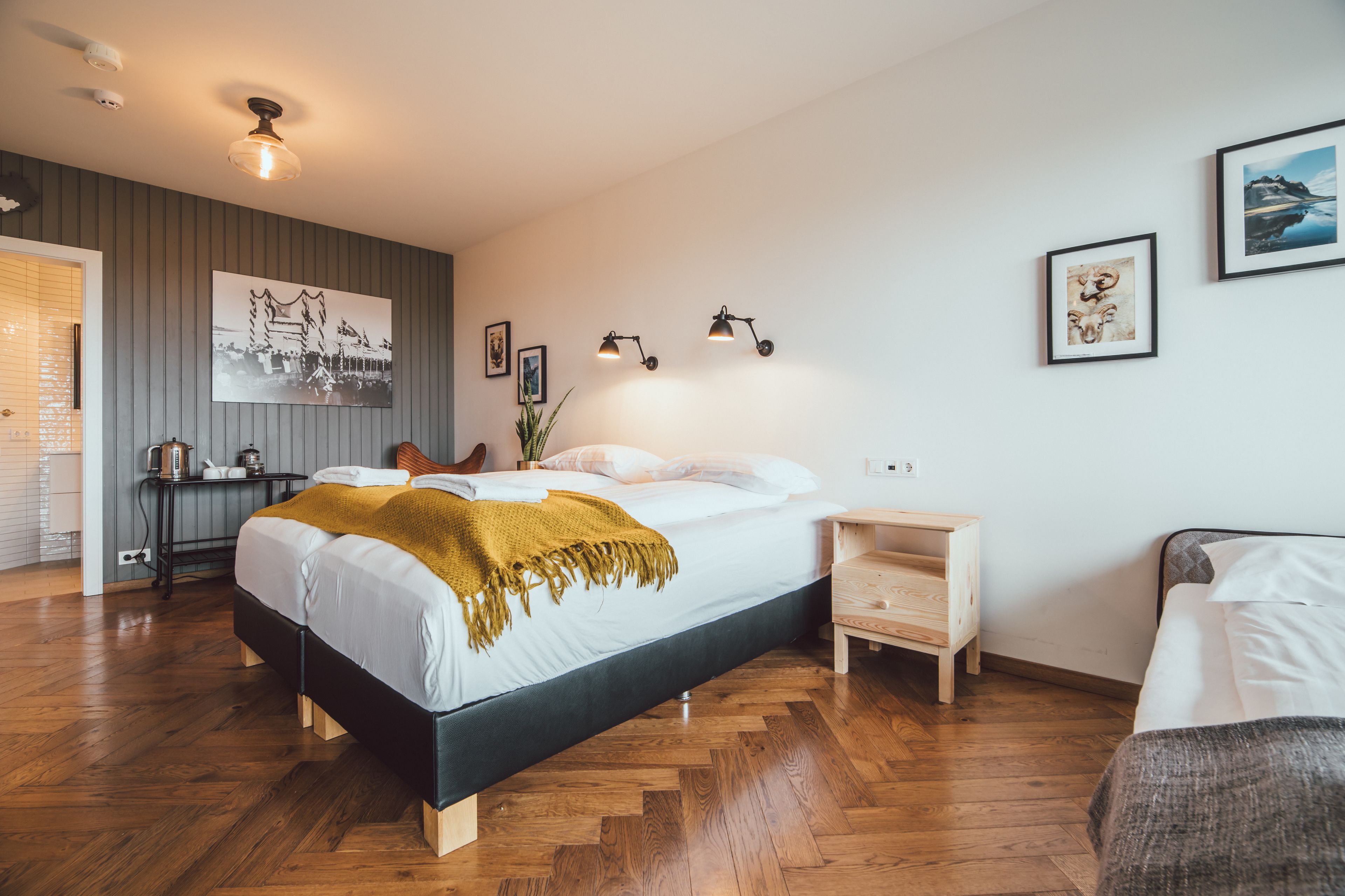 A modern bedroom with a large bed, bedside tables, a small desk, and a chair.