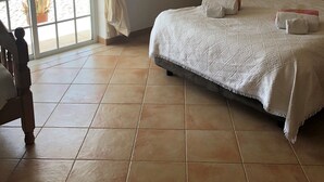 Une chambre à coucher avec un lit, une table de chevet, une fenêtre avec des rideaux et une vue sur l’extérieur.