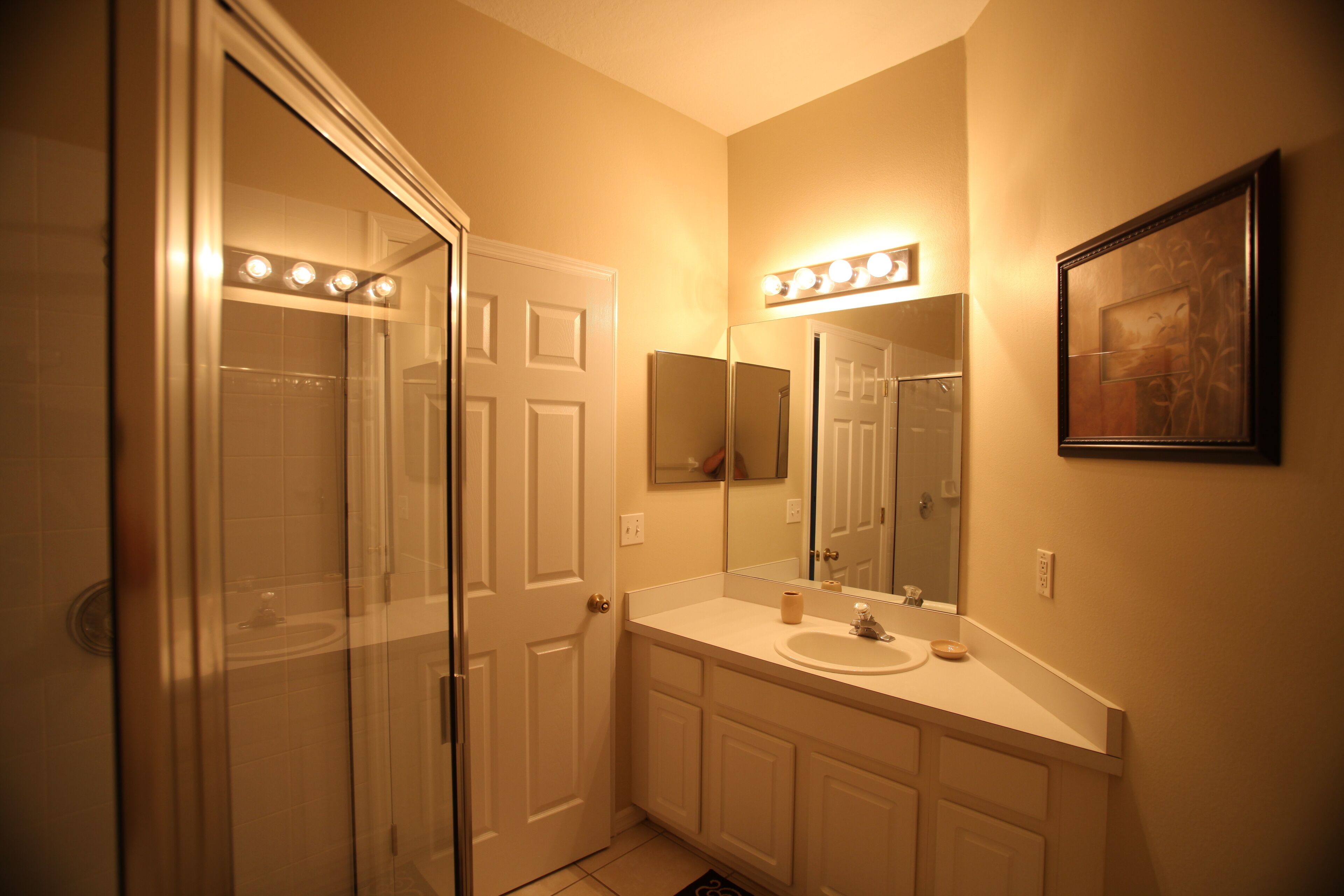 A bathroom with a glass shower enclosure, a vanity with a mirror, and a lighted vanity area.