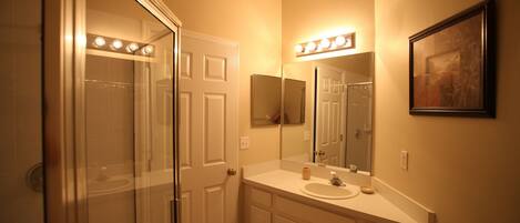 A bathroom with a glass shower enclosure, a vanity with a mirror, and a lighted vanity area.