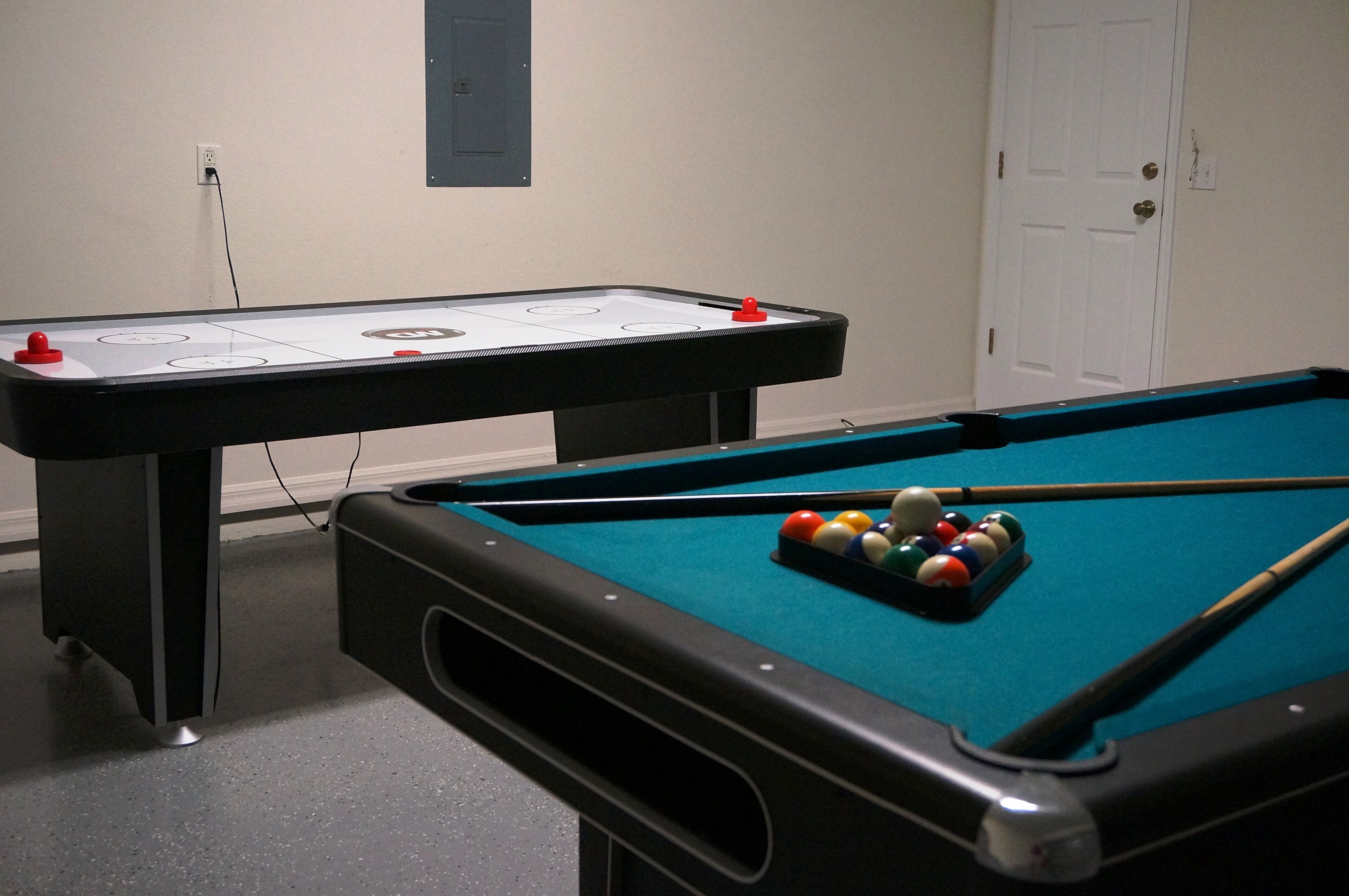 A pool table with billiard balls and a shuffleboard table with a puck.