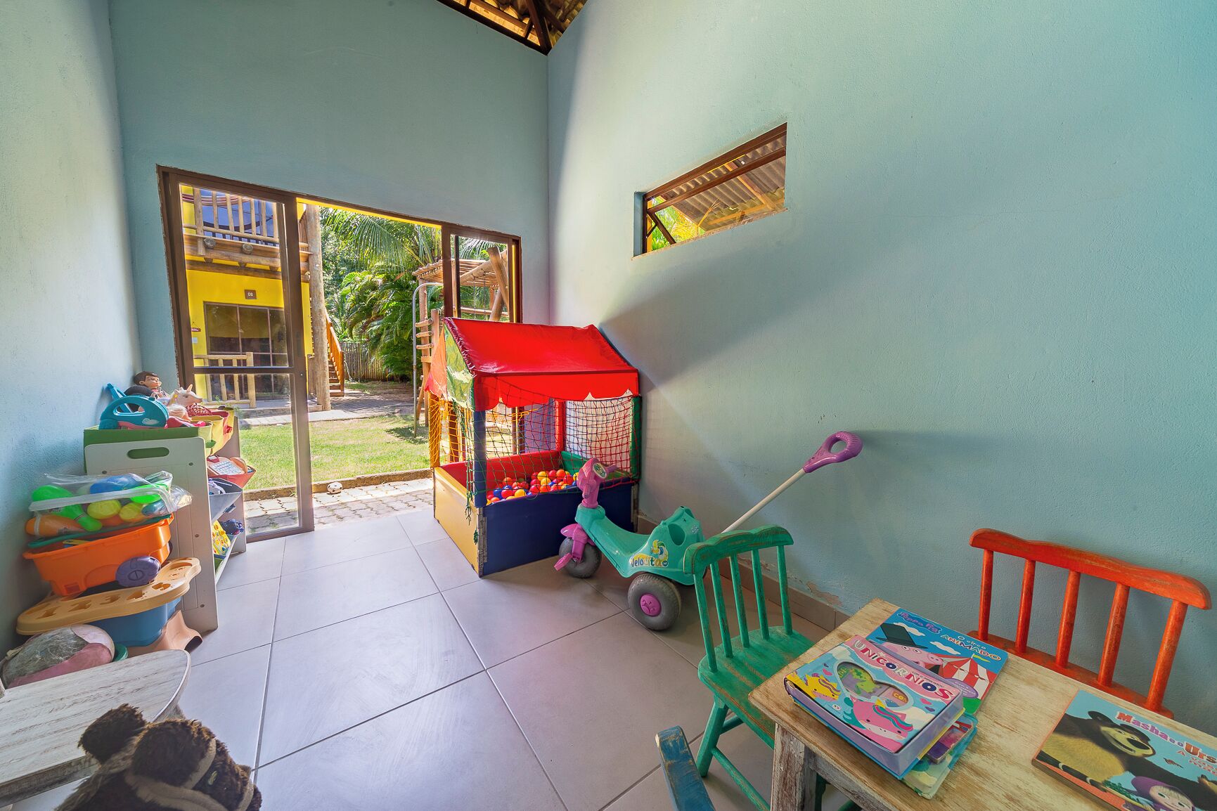 Zona infantil con piscina de pelotas, una casita y un camión de juguete.