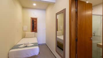 Una habitación de hotel con cama, espejo, puerta de madera y zona de ducha.