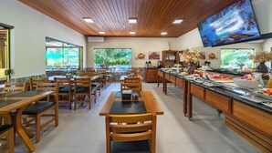Un restaurante con mobiliario de madera, un bufé y una gran pantalla de televisión.