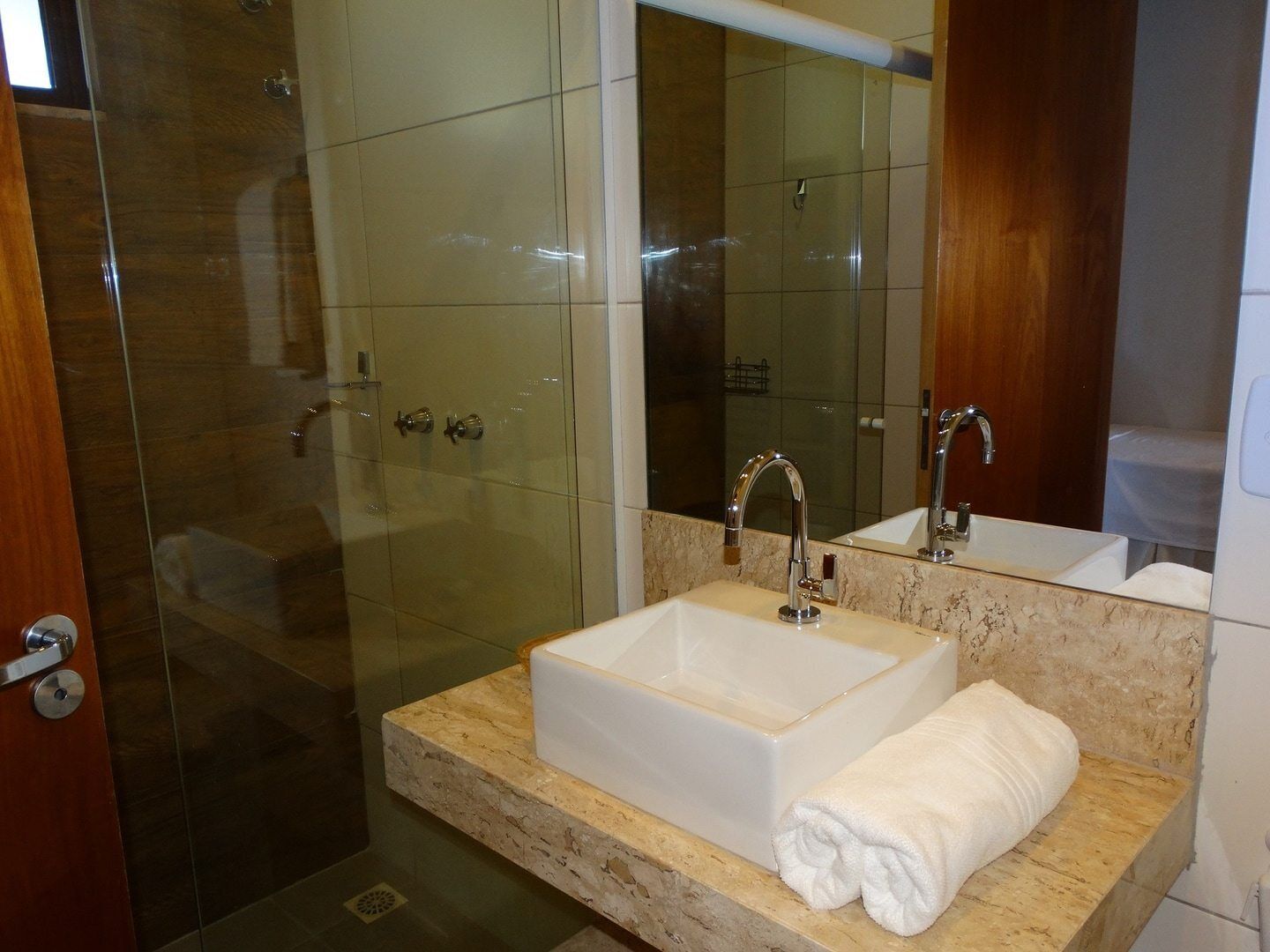 Un baño con cabina de ducha de vidrio, un lavamanos blanco y una encimera de mármol.