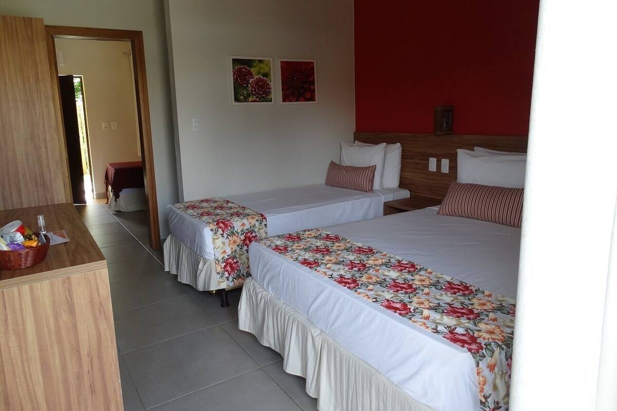 Ein Hotelzimmer mit zwei Einzelbetten, einem Holztisch und einer roten Akzentwand.