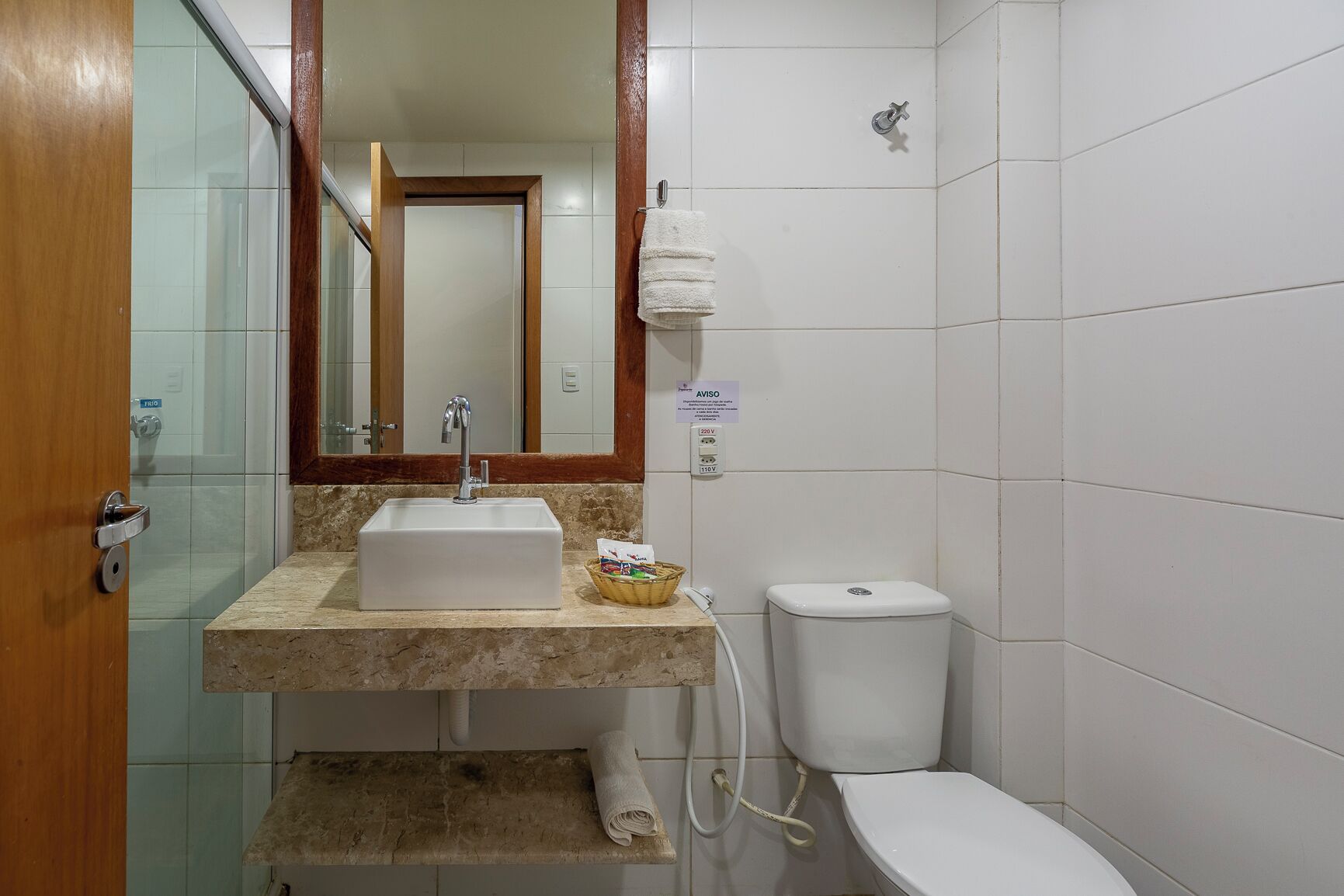 Een badkamer met een wastafel, toilet en spiegel.