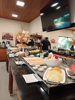 A buffet setup with various food items and a television mounted on the wall.