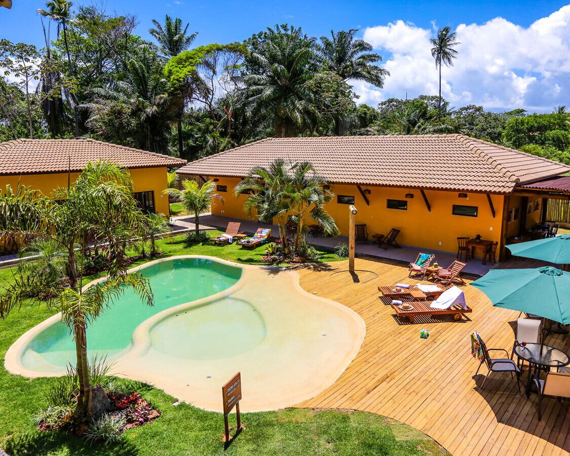 A resort with a swimming pool, lounge chairs, and a wooden deck.