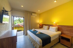 A hotel room with a bed, bedside tables, a desk, and a balcony with curtains.