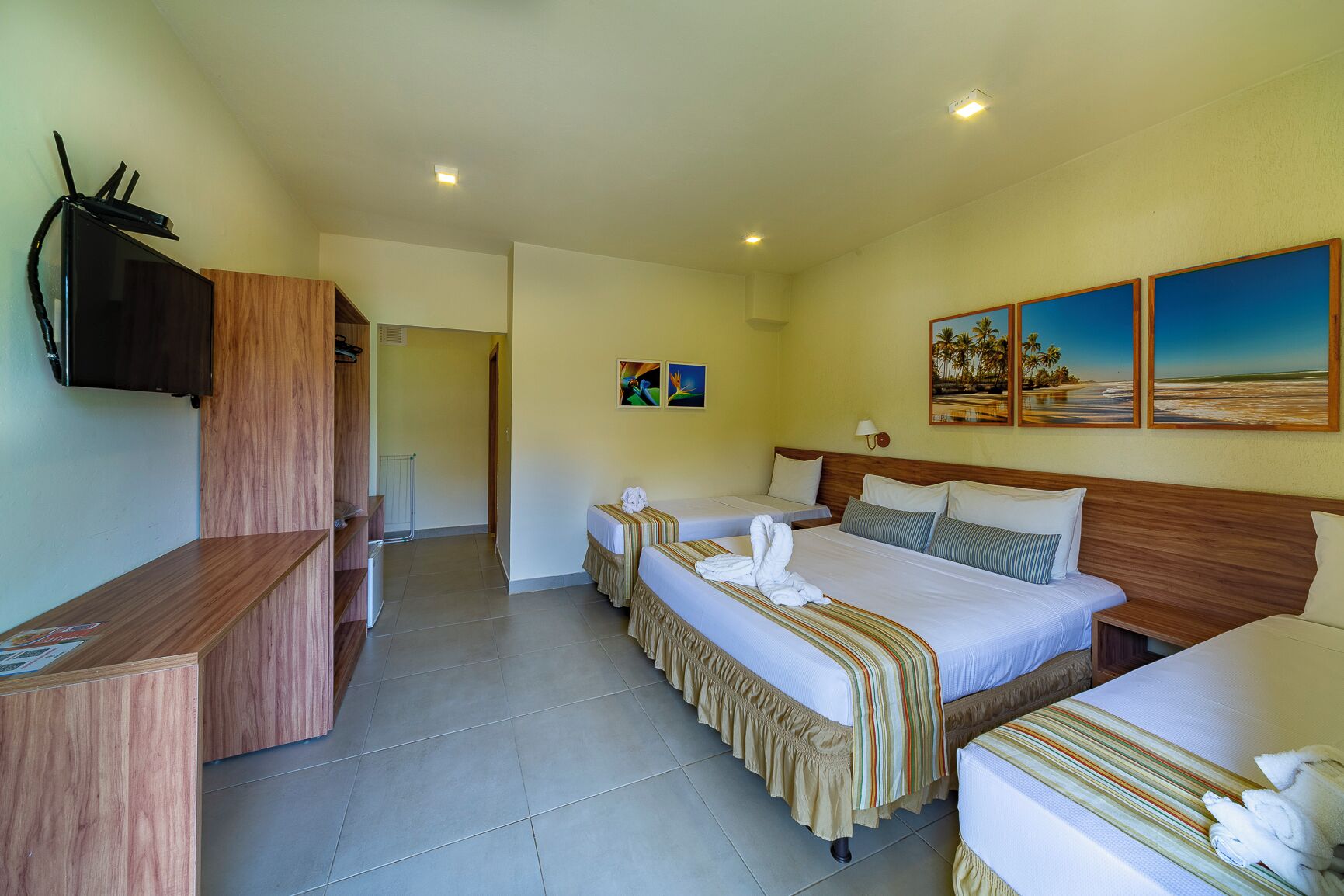 A hotel room with two beds, a TV, and artwork on the walls.