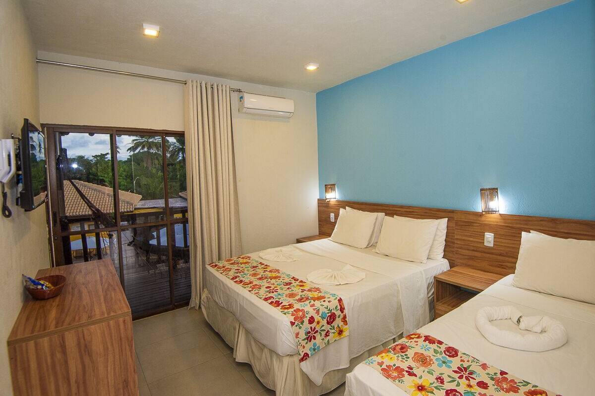 Ein Hotelzimmer mit zwei Betten, einem Holztisch, einem Balkon mit Aussicht und einer Klimaanlage.