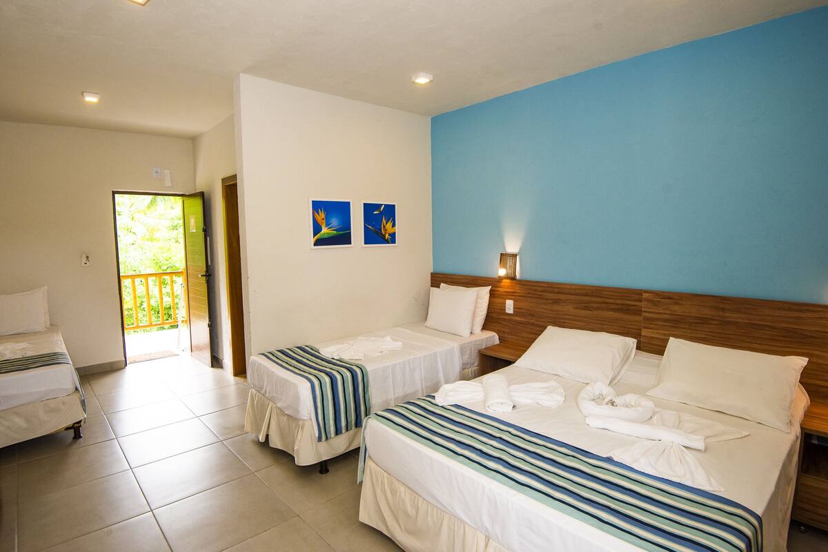 Ein Hotelzimmer mit zwei Einzelbetten, einem Kingsize-Bett und einem Balkon.