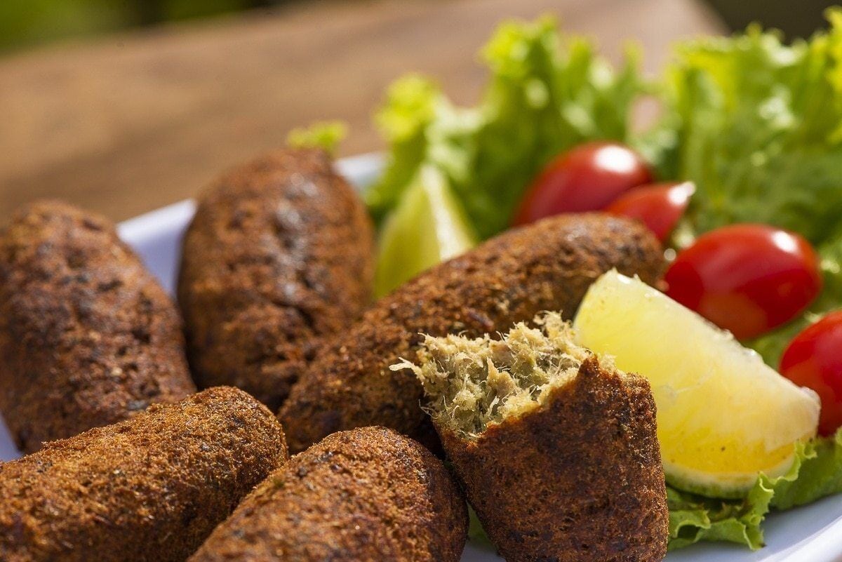A plate of fried food with a side of vegetables and a lemon wedge.