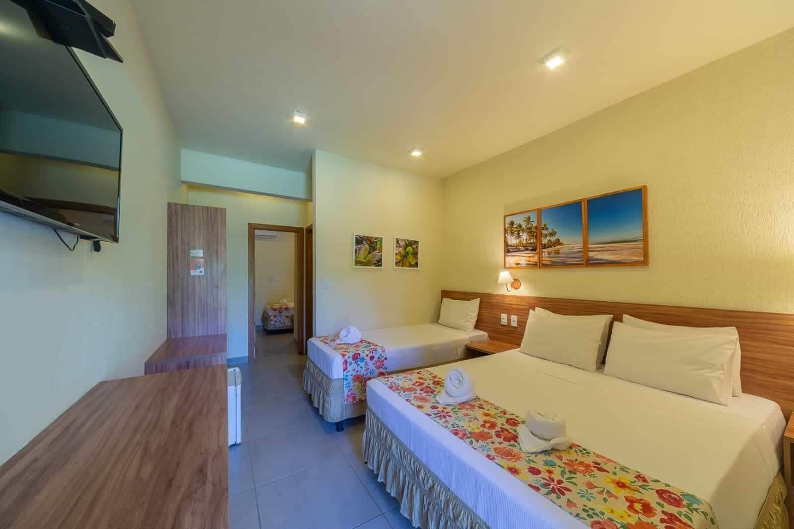 Una habitación de hotel con una cama, un escritorio, un televisor y un baño visible a través de una puerta abierta.