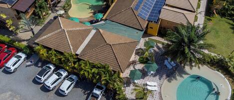 Vista aérea de un complejo turístico con varias edificaciones, una piscina y paneles solares.