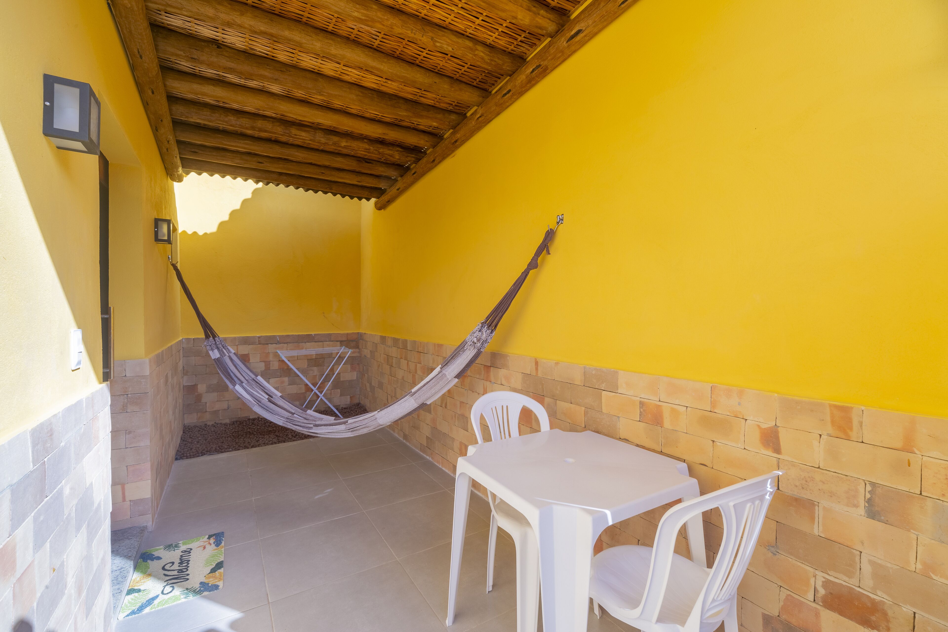 A yellow-walled room with a hammock, a table, and chairs.