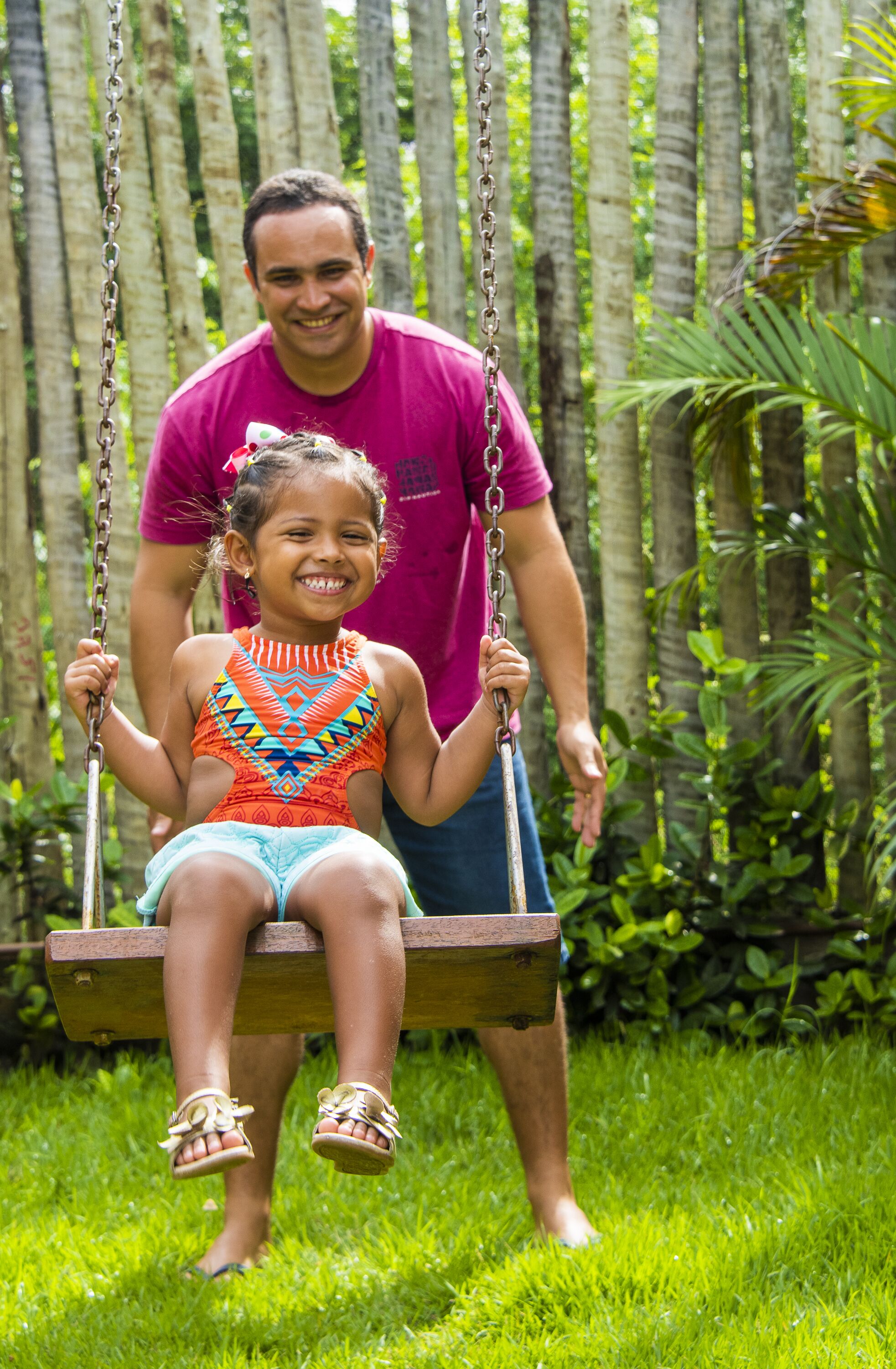 A man and a child on a swing in a lush garden.