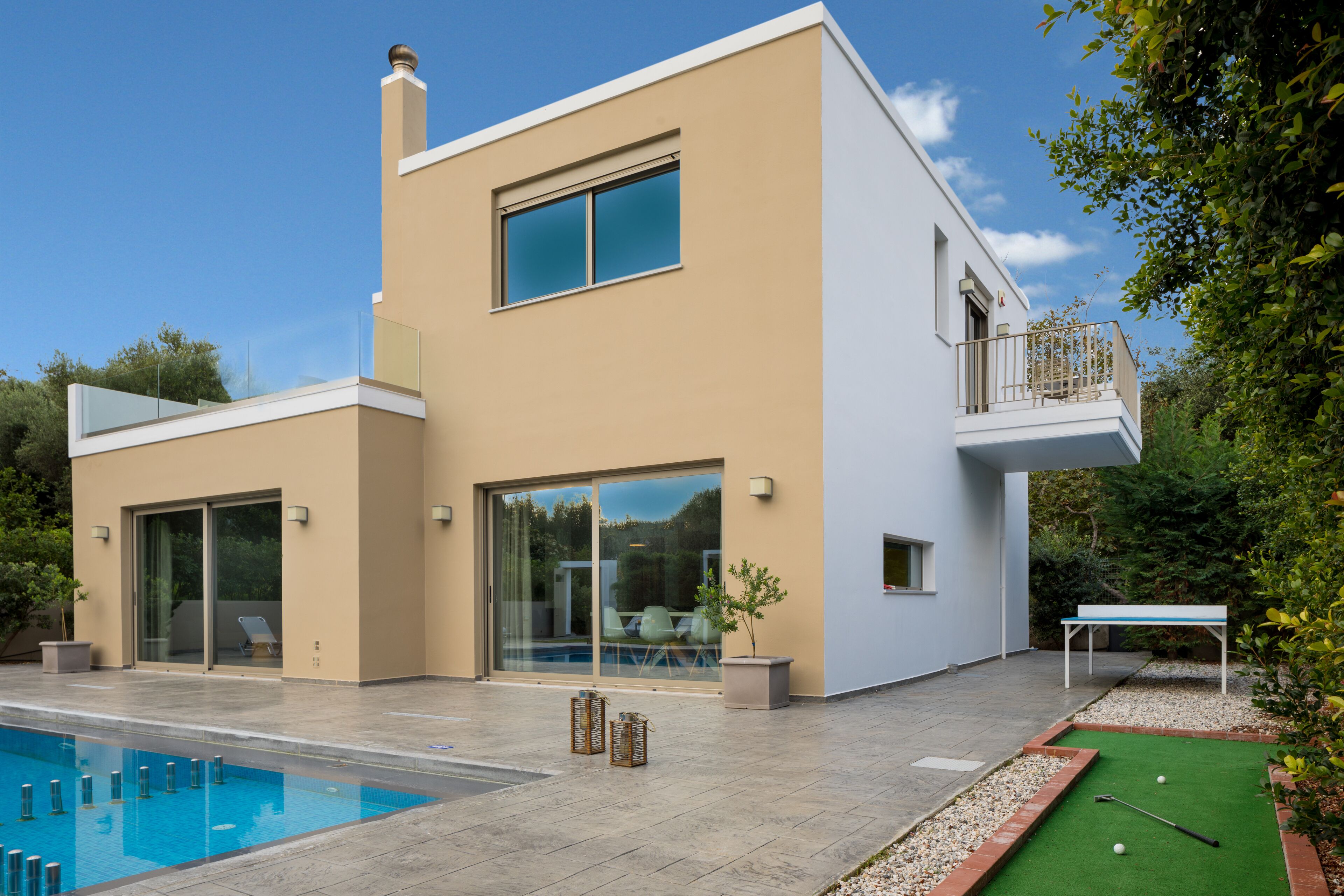 A modern two-story house with a swimming pool, a tennis court, and a balcony.