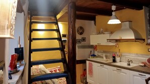 Eine Küche mit einer Holztreppe, einem weißen Herd und einer hängenden Leuchte.