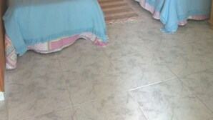 Une chambre avec deux lits en bois, une table de chevet et un climatiseur fixé au mur.