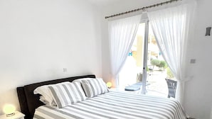 A bedroom with a bed, a bedside table, and a window with curtains.