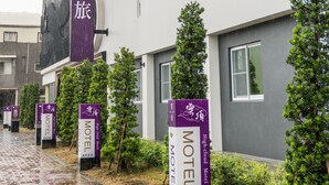 A modern building with a prominent 'Motel' sign and a large purple banner with Chinese characters.
