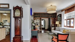 A living room with a large wooden clock, a sofa, a chair, and a bookshelf.