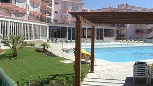 Un espace aménagé au bord de la piscine, avec une pergola en bois, des chaises longues et une piscine à l’eau d’un bleu cristallin.