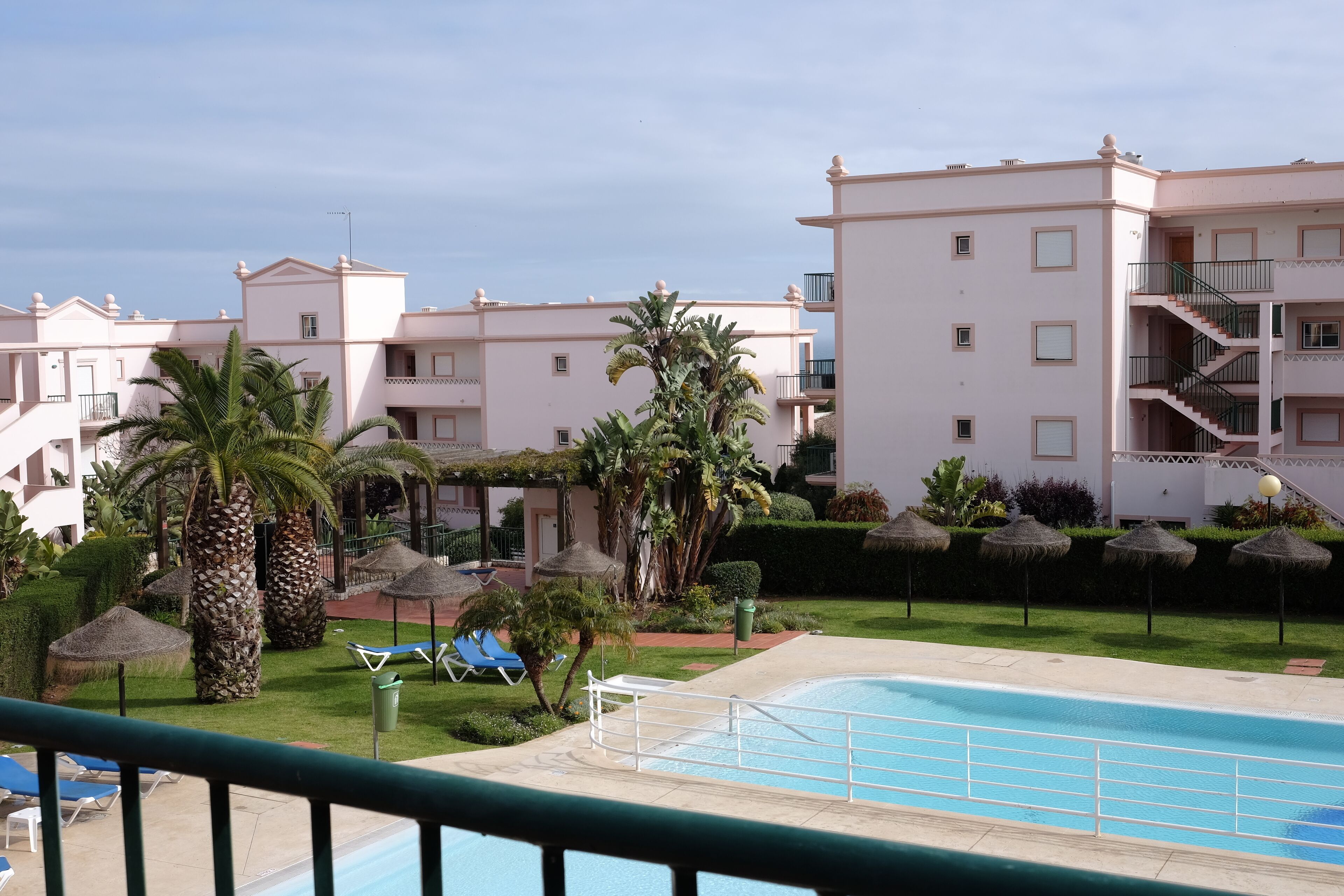 Un resort con piscina, palmeras y un césped bien cuidado.