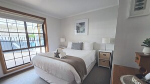 Une chambre à coucher bien aménagée, avec un grand lit, des tables de chevet, une lampe et une vue par la fenêtre.