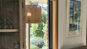 Un salon comprenant un canapé, une table basse, un meuble contenant de la verrerie, et une grande fenêtre donnant sur un paysage verdoyant.
