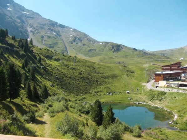 A mountainous landscape with a lake, a building with a modern design, and a clear sky.