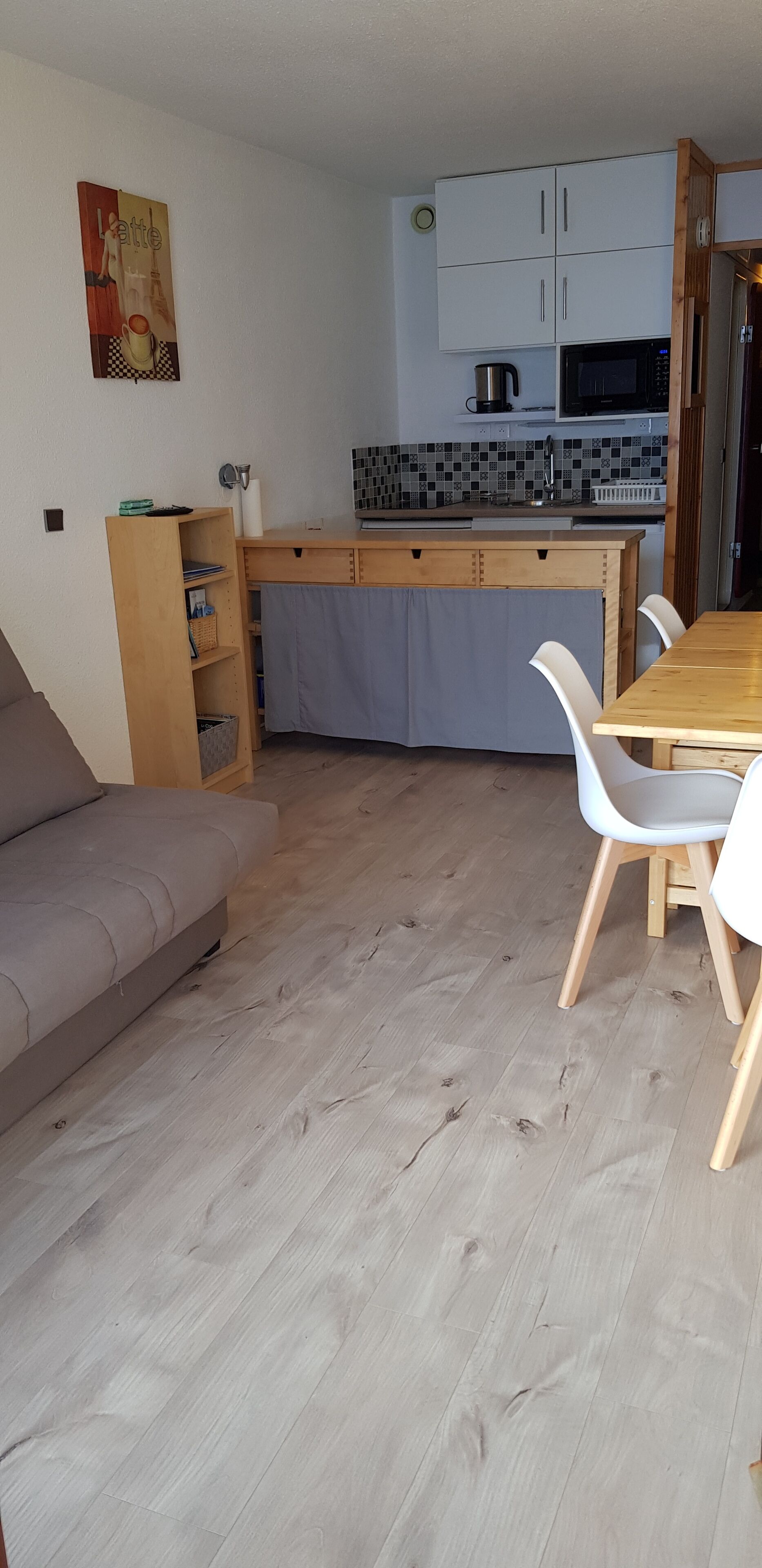 A compact living space with a kitchenette, a dining area, and a sofa.