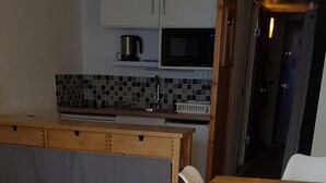 Ein Holztisch mit weißen Stühlen, eine geflieste Spritzschutzleiste und eine Mikrowelle darüber.