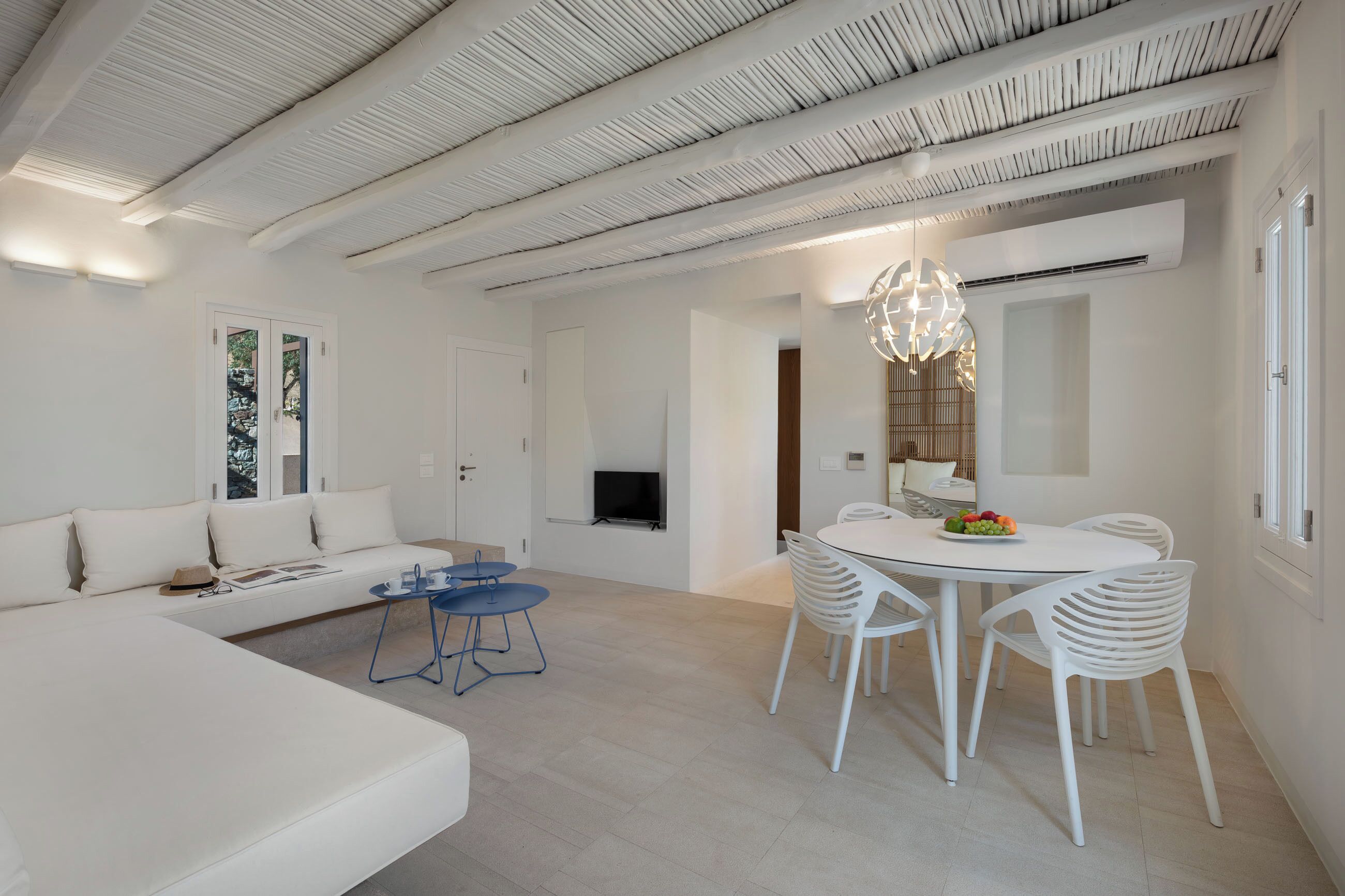 A modern, white-themed living and dining area with a sofa, dining table, and chairs.
