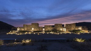 A series of stone buildings with illuminated entryways, set against a twilight sky.