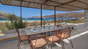 An outdoor dining area with a view of the sea and hills.