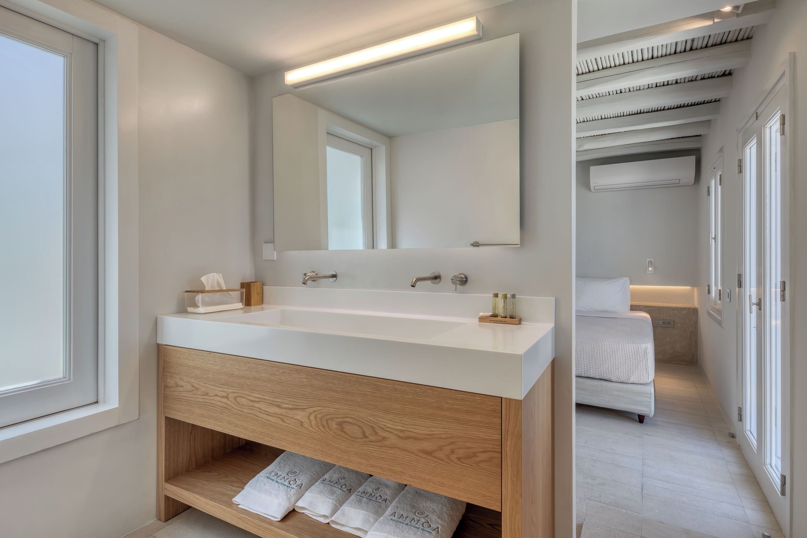 Un baño moderno con un espejo grande, lavamanos blanco y tocador de madera.