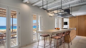 A modern kitchen with a large island, bar stools, and a view of the beach.