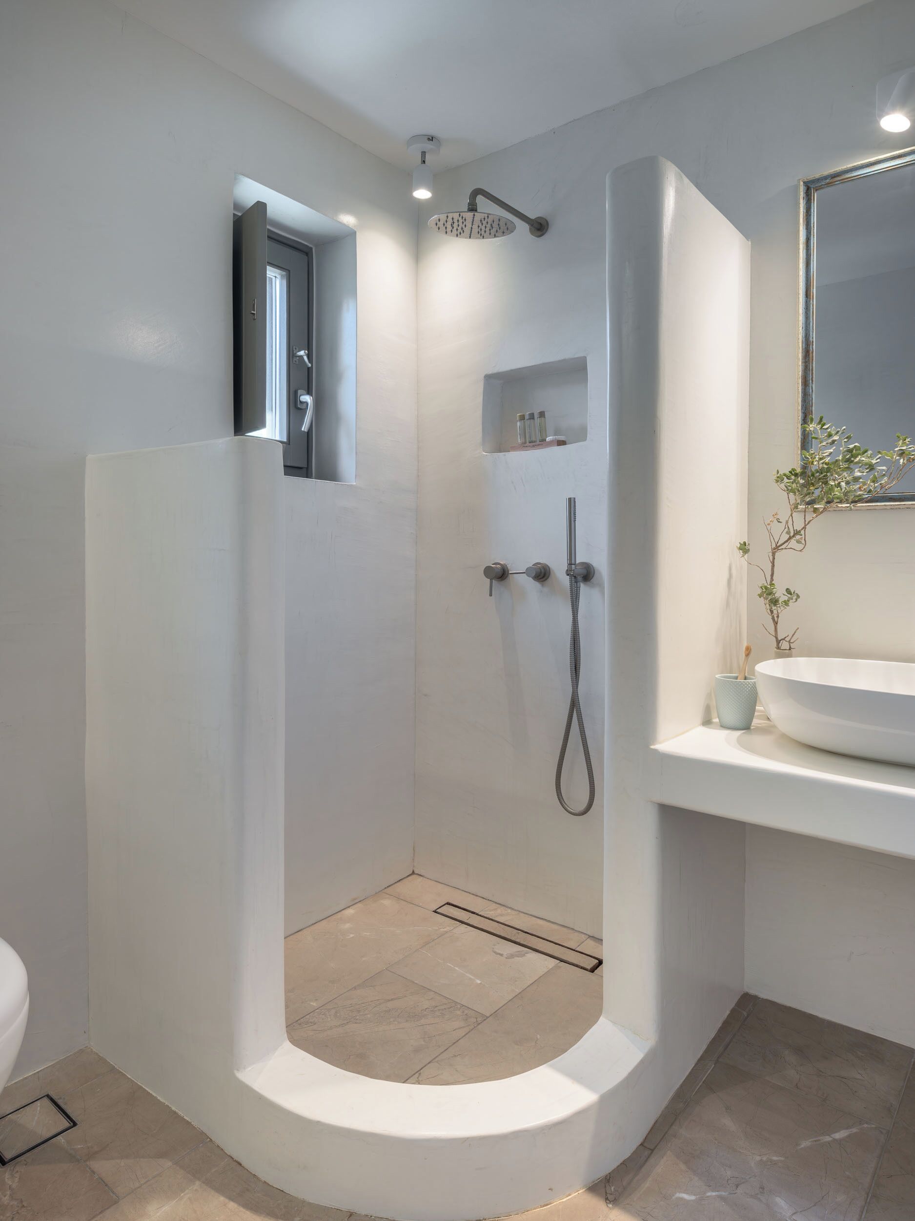 A modern bathroom with a walk-in shower, a toilet, and a sink with a mirror.