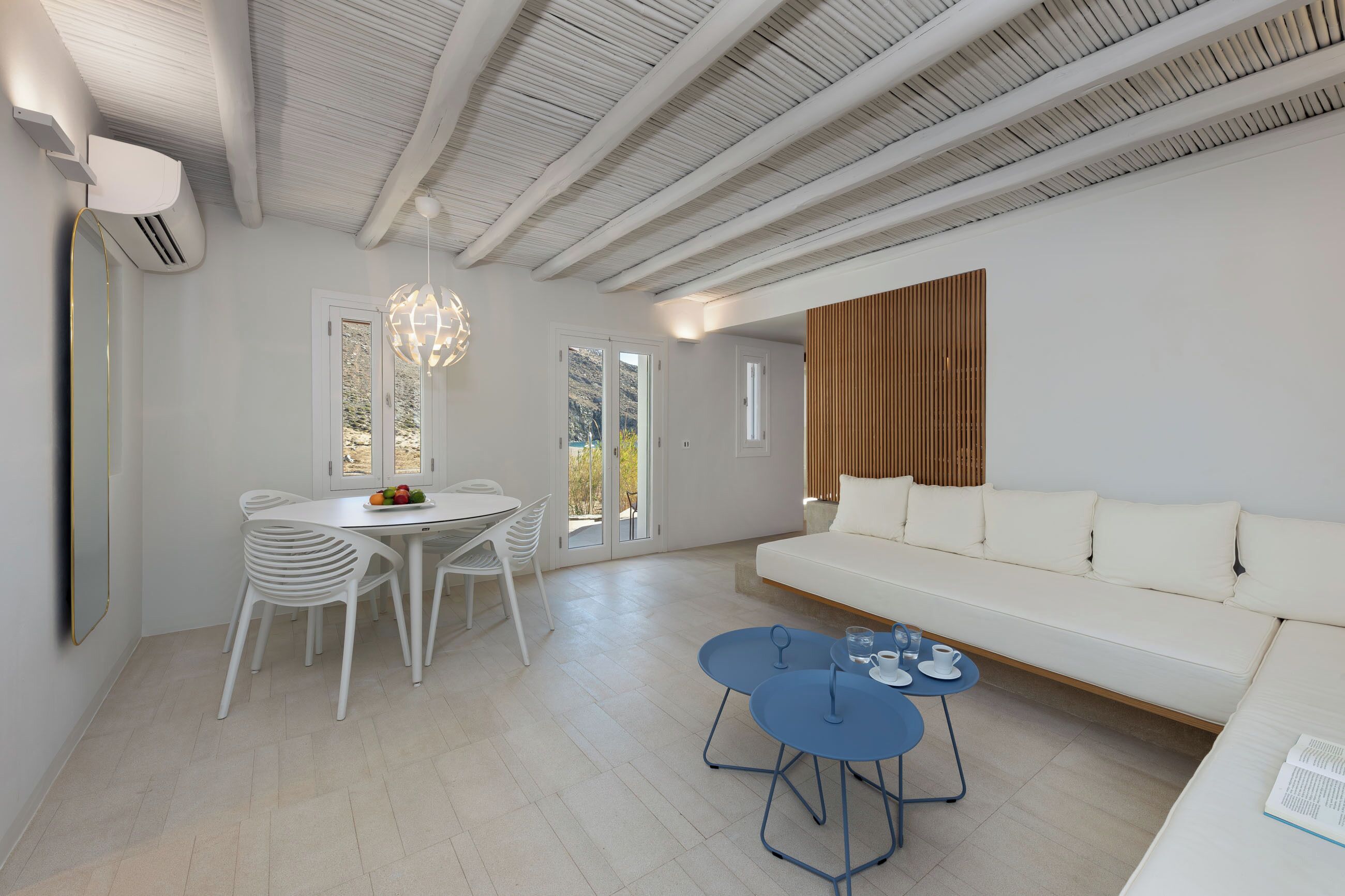 A modern living room with a white sofa, a dining table with chairs, and a blue coffee table.
