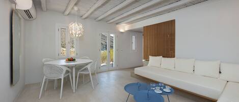 A modern living room with a white sofa, a dining table with chairs, and a blue coffee table.