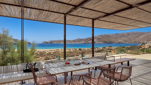 An outdoor dining area with a view of the sea and hills.