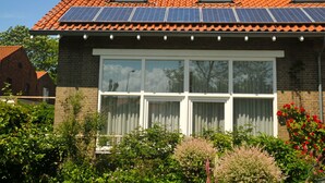 Una casa con techo de tejas, ventanas amplias y paneles solares.