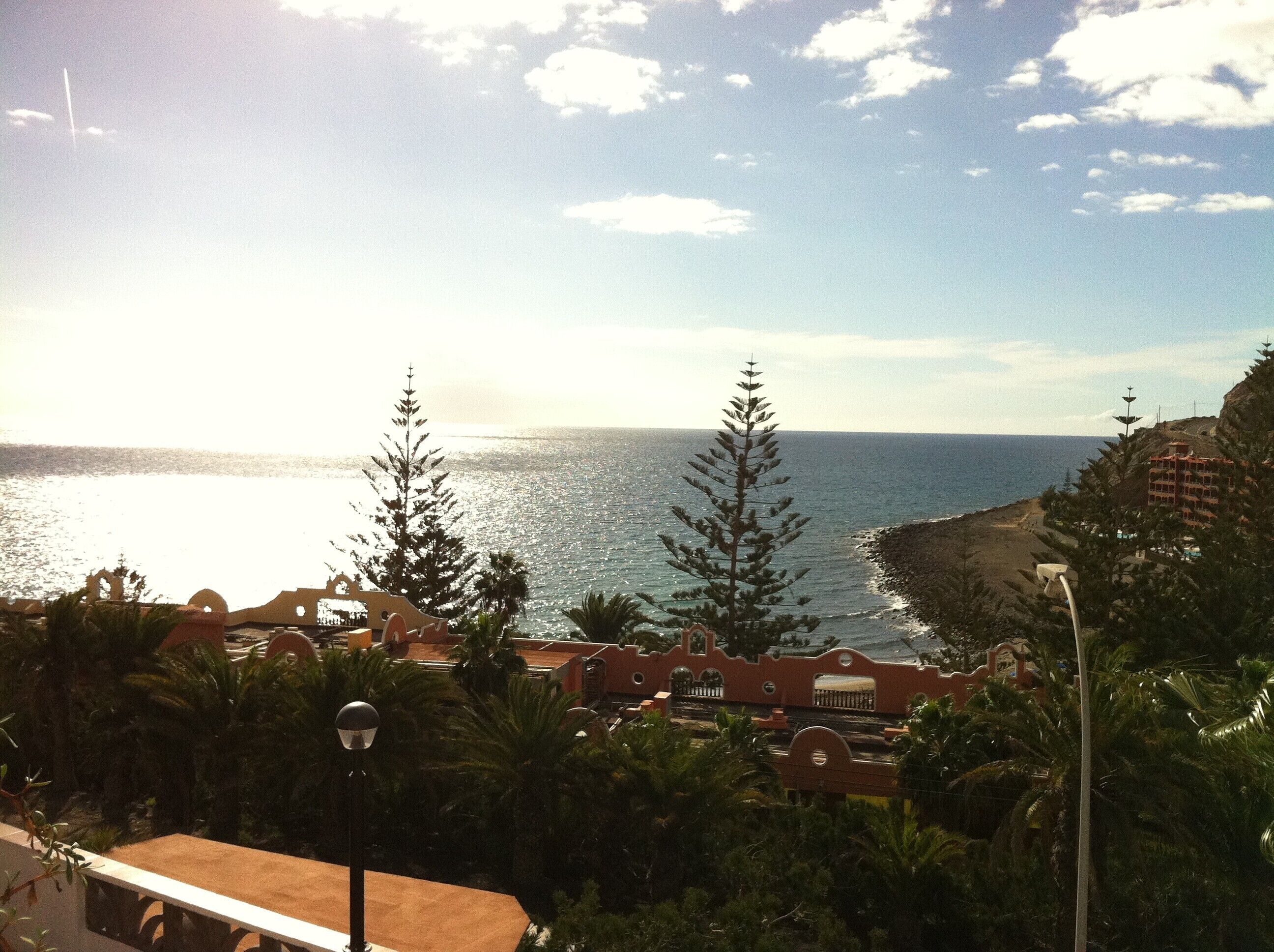 A coastal view with a clear sky, a beach, and a building with a red facade.